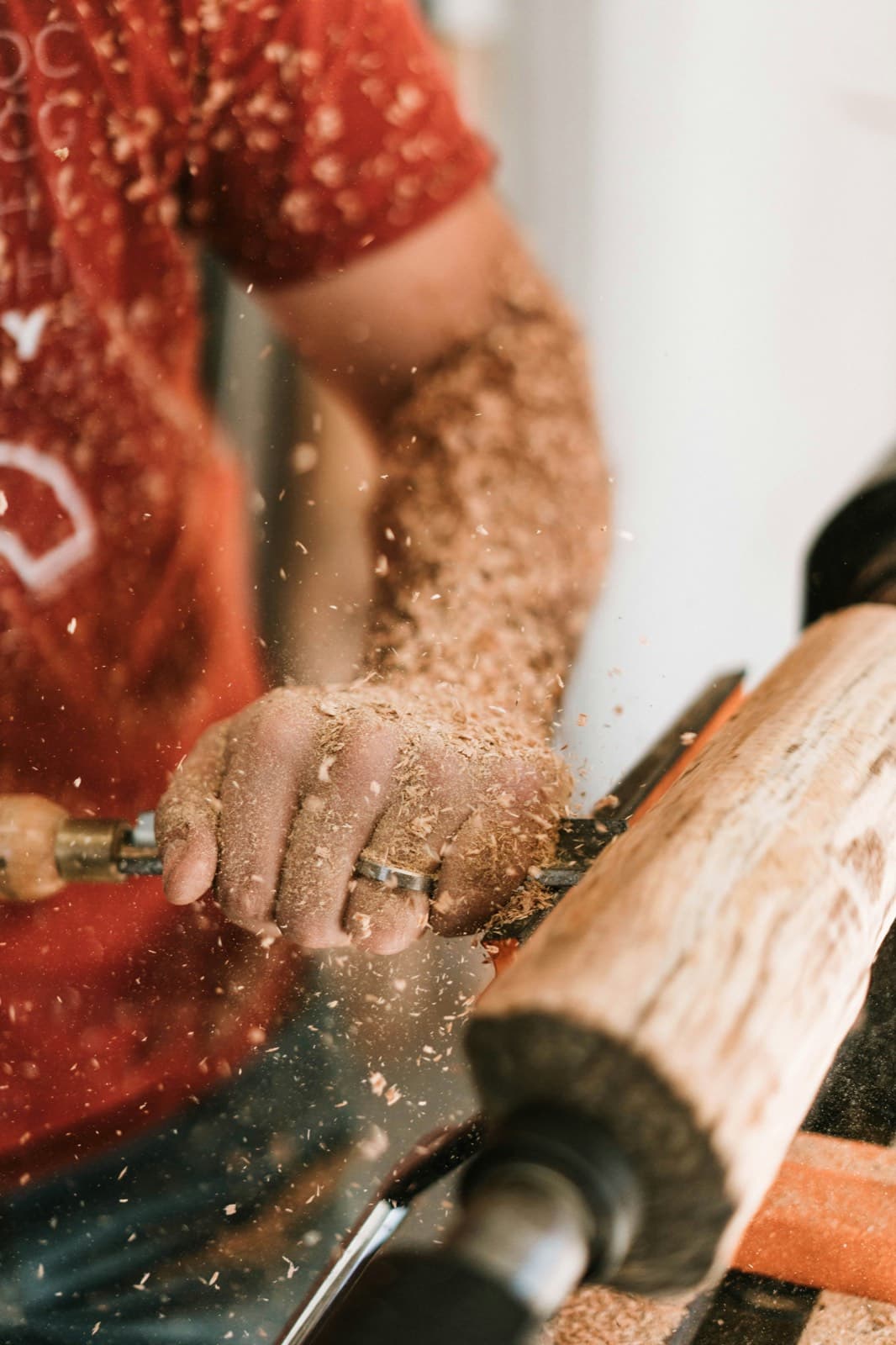 A woodturner at a lathe, shavings flying, shaping a length of timber